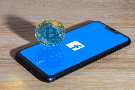 Bitcoin coin with the Facebook logo screen backgroundのeditorial素材