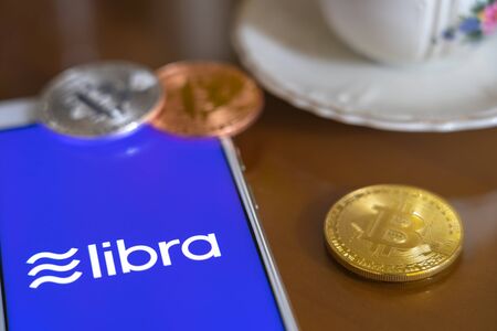 Bitcoin Coin with the Facebook's Libra Crypto Coin logo on smartphone screen backgroundのeditorial素材