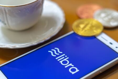Bitcoin Coin with the Facebook's Libra Crypto Coin logo on smartphone screen backgroundのeditorial素材