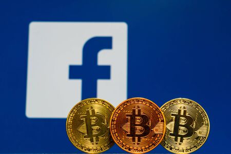 Gold Bitcoin coins with the Facebook logo on background screen.のeditorial素材
