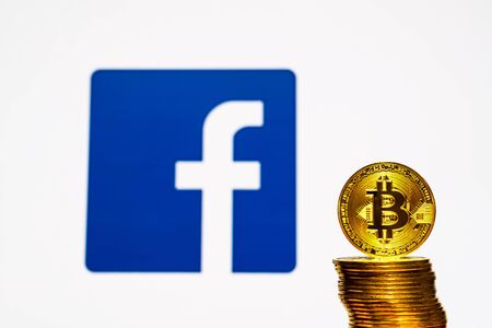 Gold Bitcoin coins with the Facebook logo on background screen.のeditorial素材
