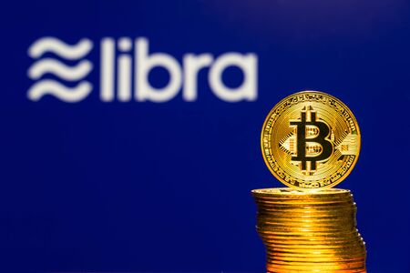 Gold Bitcoin Coins with the Facebook Libra Crypto Coin logo on background screen.のeditorial素材