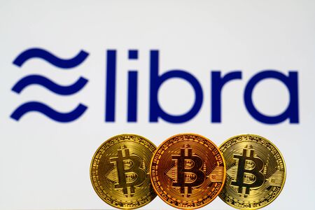 Gold Bitcoin Coins with the Facebook Libra Crypto Coin logo on background screen.のeditorial素材