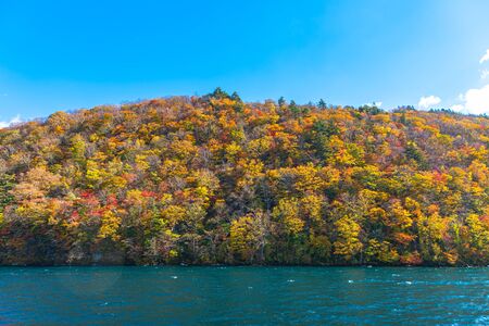 Beautiful autumn foliage scenery  with Clear blue sky, water, white cloud at Aomori, Japanの写真素材
