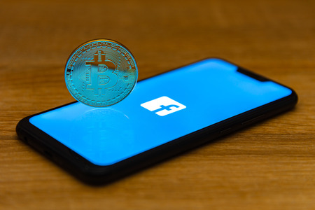 Bitcoin coin with the Facebook logo on a smartphone screenのeditorial素材