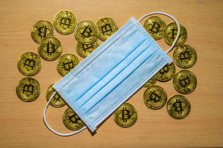 Gold Bitcoin coins with a medical mask. A business finance conceptのeditorial素材