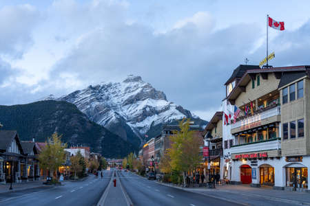 Street view of Banff Avenue in autumn and winter season night. Snow Capped Cascade Mountain in the background. Banff, Alberta, Canada.のeditorial素材
