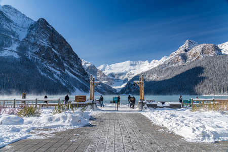 Fairmont Chateau Lake Louise in early winter sunny day morning. Mist floating on turquoise color water surface. Clear blue sky, snow capped mountains in background.のeditorial素材