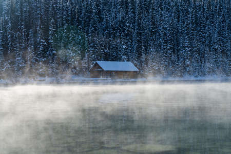 Lake Louise boathouse in early winter sunny day morning. Mist floating on turquoise color water surface. Banff National Park.のeditorial素材