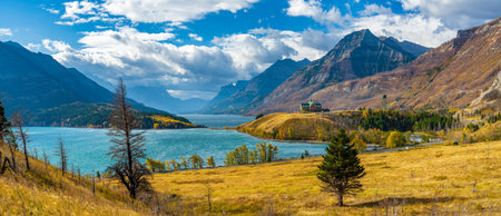 Middle Waterton Lake lakeshore in autumn foliage season sunny day morning. Blue sky, white clouds over mountains in the background. Landmarks in Waterton Lakes National Park, Alberta, Canada.のeditorial素材