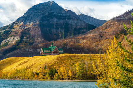 Middle Waterton Lake lakeshore in autumn foliage season sunny day morning. Blue sky, white clouds over mountains in the background. Landmarks in Waterton Lakes National Park, Alberta, Canada.のeditorial素材