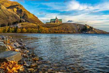 Waterton Lakes National Park lakeshore in autumn foliage season morning. Sunny blue sky and colourful clouds, beautiful fall color landscape. Landmarks in Alberta, Canada.のeditorial素材
