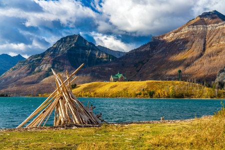 Driftwood Beach, Middle Waterton Lake lakeshore in autumn foliage season morning. Blue sky, white clouds over mountains in the background. Landmarks in Waterton Lakes National Park, Alberta, Canada.のeditorial素材