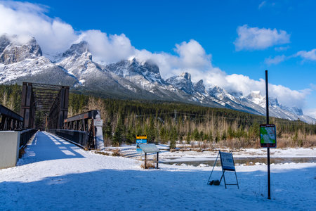 Canmore, AB, Canada-OCT 24 2020: Canmore Engine Bridge in early winter season sunny day morning. Clear blue sky, snow capped Mount Rundle mountain range in background.のeditorial素材