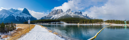 Canmore, AB, Canada-OCT 24 2020: Rundle Forebay Reservoir in winter sunny day morning. Clear blue sky, snow capped Mount Rundle and Mount Lawrence Grassi mountain range in background.のeditorial素材