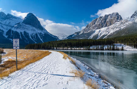 Rundle Forebay Reservoir in winter sunny day morning. Clear blue sky, snow capped Mount Rundle and Mount Lawrence Grassi mountain range in background.のeditorial素材