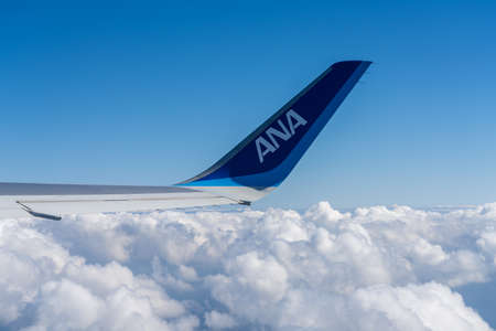 All Nippon Airways (ANA) Airplane wing with blue sky white clouds horizon in the background.のeditorial素材