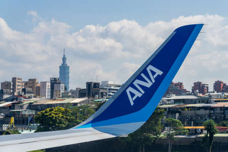All Nippon Airways (ANA) Airplane wing with Taipei city skyline in the background. Taipei, Taiwanのeditorial素材