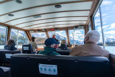 Jasper, Alberta, Canada-June 17 2021: Maligne Lake Cruise in summer during covid-19 pandemic period. Passengers and tourist guide wearing face masks inside the boat.のeditorial素材