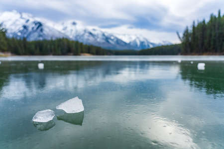 Johnson Lake frozen water surface in winter time. Snow-covered mountain in the background. Tourists here doing ice-skating in this season. Banff National Park, Canadian Rockies, Alberta, Canada.の写真素材