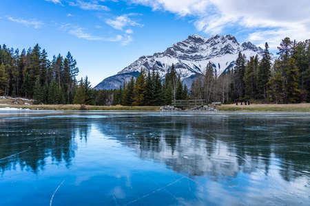 Johnson Lake frozen water surface in winter time. Snow-covered Cascade Mountain in background. Banff National Park, Canadian Rockies, Alberta, Canada.の写真素材