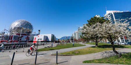 Vancouver, BC, Canada - April 16 2021 : People walking and cycling on Creekside Park seawall trail in springtime sunny day. Science World and cherry blossom.のeditorial素材