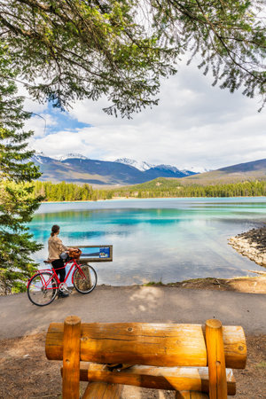Alberta, Canada - May 9 2021 : Young girl cycling in Lake Annette lakeshore enjoying the nature scenery. Summer time in Jasper National Park, Canadian Rockies.のeditorial素材