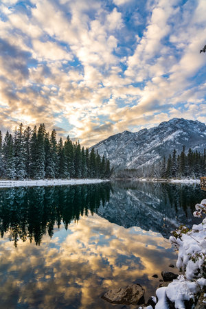 Banff National Park beautiful natural scenery in winter sunset time. Mount Norquay with colorful clouds reflected on Bow River like a mirror. Town of Banff, Canadian Rockies.の写真素材