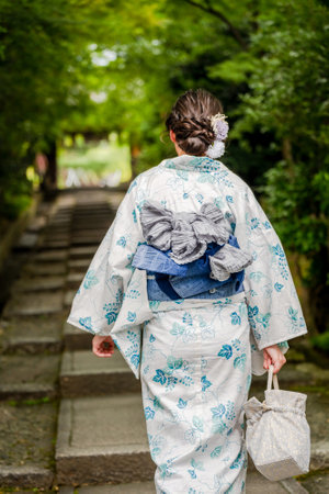 Japanese woman wearing traditional kimono walking down the stairs in the gardenの写真素材