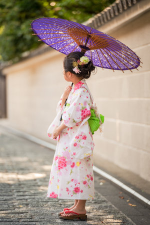 Japanese girl in traditional kimono with umbrella in the street.の写真素材
