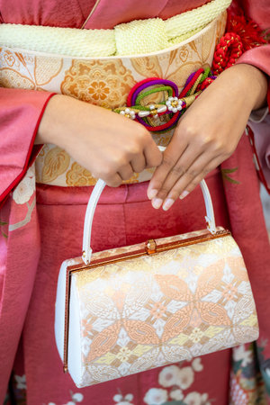 Elegant Pink Traditional Japanese Kimono Furisode with Intricate Floral Detailing, Featuring Graceful Hands and a Chic Bag.の写真素材