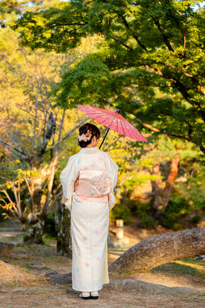 Woman in Kimono holding a traditional Japanese parasol (Wagasa) in a beautiful Japanese garden, Kyotoの写真素材