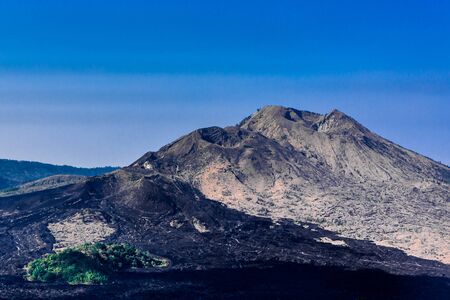 The peak of Mount Batur, an active volcano in Bali, Indonesia underneath a blue skyの写真素材