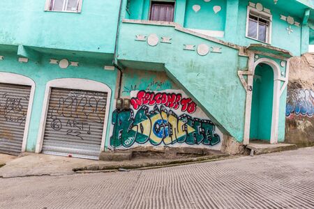 Welcome to Rocinha graffiti & Brazilian flag on a green building building on a steep road in Rocinha...