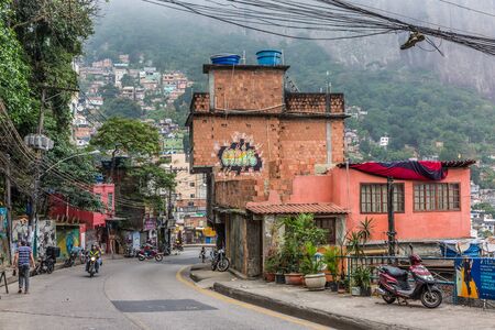 A street view looking down a road with scooters & graffiti on the wall of a building in Rocinha favela, a shanty town or slum in Rio de Janeiro, Brazil, South Americaのeditorial素材