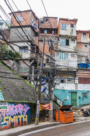 Urban street in the middle of Rochina favela, known as a shanty town or slum, electrical utility...
