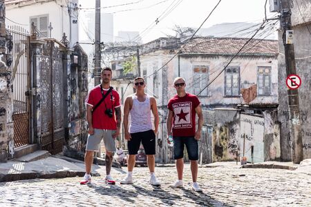 Three young guys or tourists stood posing on a road during daytime in an urban grungy street in the Lapa neighbourhood in central Rio de Janeiro in Brazil, South Americaのeditorial素材