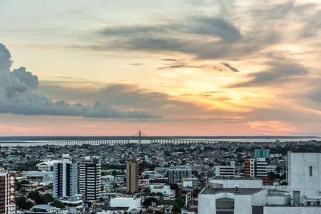 Aerial view at sunset with a beautiful cloudy sky over the urban city of Manaus in the Amazon, Brazil, with high rise buildings & the Rio Negra bridge over the Rio Negra river in the backgroundのeditorial素材
