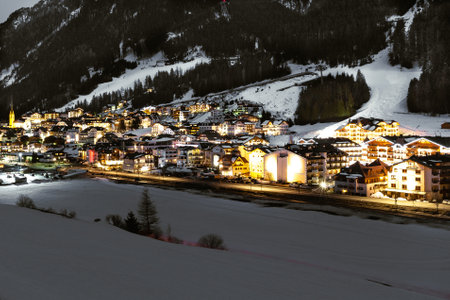 Ischgl ski resort village in Austria illuminated and lit up at night while surrounded by snow and forestの写真素材