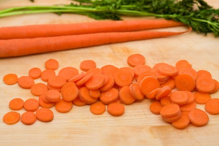 Cut and whole carrots on wodden cutting boardの写真素材