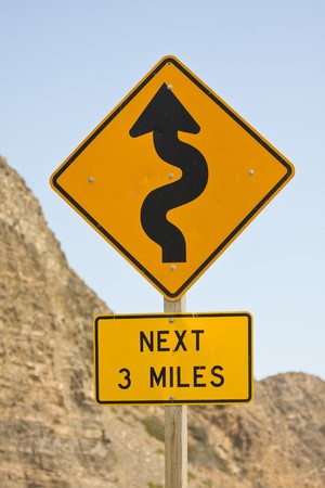 Orange traffic sign warning of winding roadの写真素材
