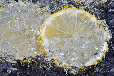 Slices lemon with crushed ice on black backgroundの写真素材
