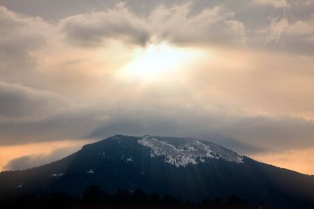 God rays during sunset over mountain silhouetteの写真素材