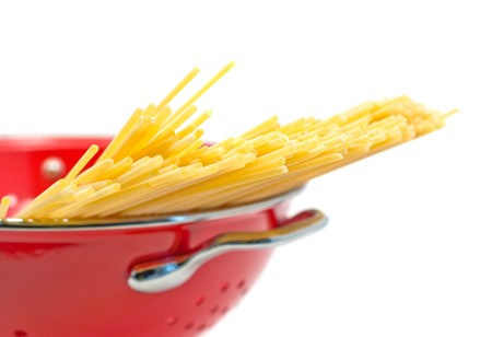 Raw spaghetti in strainer over white backgroundの写真素材