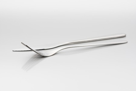 Fork and knife with reflection on metallic background