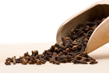 Cloves on wooden scoop on wooden cutting boardの写真素材