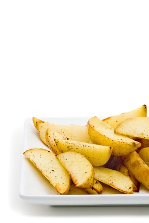 Fresh handmade potato wedges on plate over white backgroundの写真素材