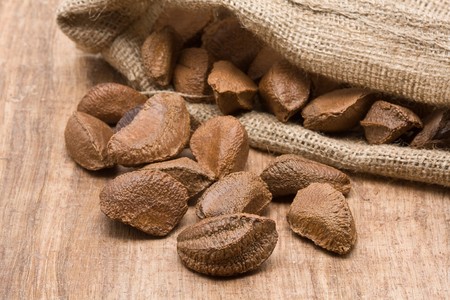 Brazil nuts in burlap sack on wooden tableの写真素材