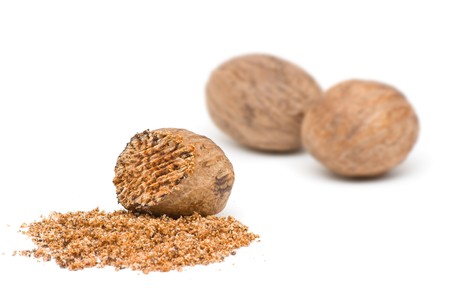 Nutmegs whole and grind over white backgroundの写真素材
