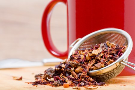 Dried fruit tea in tea strainer with cup of tea